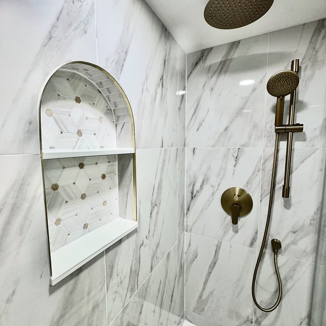 Arched shower niche with hexagon mosaic tile and brass trim