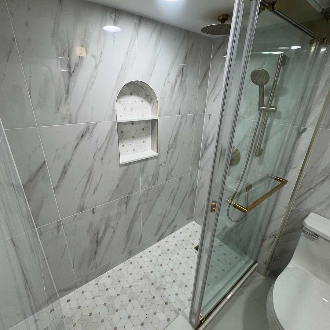 Walk-in shower with hexagon mosaic floor and a gold-framed glass door