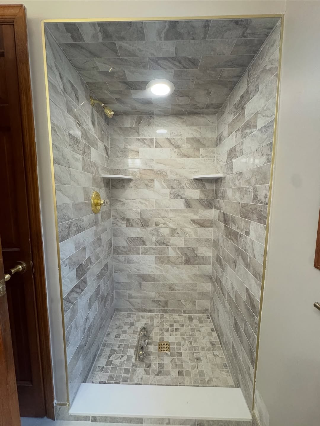 Gray stone-look shower alcove with a tiled ceiling and brass fixtures